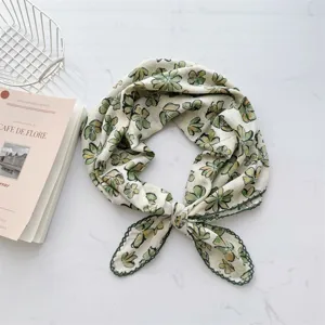 Close-up of a floral cotton square scarf with delicate green stitched lace edges.
