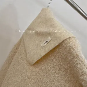 Detailed view of cream wool blend knit triangle scarf featuring a soft texture