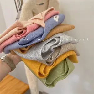 Soft wool knit triangle scarves in a colorful stack showing various pastel tones.