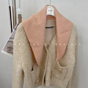 Detail of a soft pink wool blend knit triangle scarf on a cream cardigan.