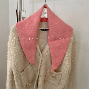 Detailed view of a soft pink wool knit triangle scarf styled with a cream cardigan