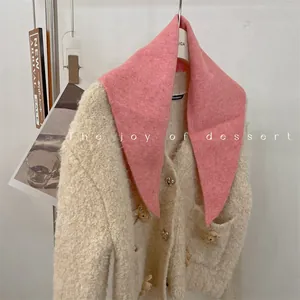 Close-up of pink wool blend knit triangular scarf draped on a fuzzy cardigan.