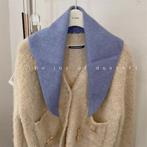 Detailed view of a soft blue knitted triangular scarf paired with a beige teddy bear cardigan