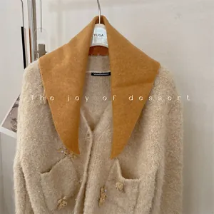 Detail of fuzzy wool cardigan with cute bear decorations and ginger knit scarf