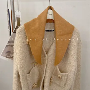 Close-up of mustard yellow wool blend triangular scarf paired with knit cardigan.