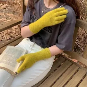 Nahaufnahme von gelben Strickhandschuhen aus Kaninchenhaar beim Lesen eines Buches im Freien.