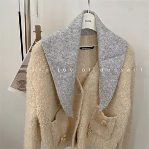 Close-up detail of wool blend grey triangle scarf paired with cream knit cardigan