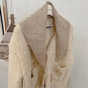 Detailed view of a soft beige wool-blend knit triangle shawl with a minimalist design