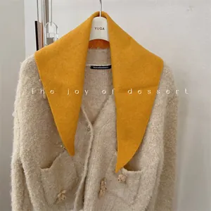 Close-up of bright yellow wool blend knit triangle scarf styled on a beige sweater
