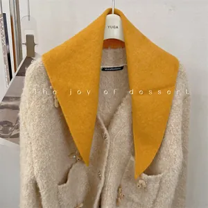Detailed view of a vibrant yellow wool blend triangular scarf paired with a soft cardigan.