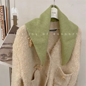 Close-up detail of a soft green wool blend knit triangle scarf styled on a beige cardigan