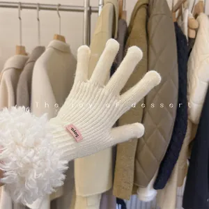 Close-up of white knitted glove with plush lamb wool cuff and decorative pink tag
