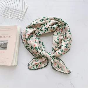 Detailed view of floral cotton neck scarf featuring delicate green lace edges on marble