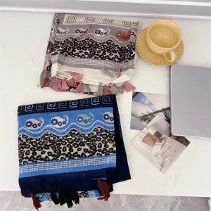 Lifestyle view of two oversized ethnic tassel scarves featuring leopard and paisley prints