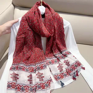 Close-up detail of red ethnic style scarf with floral patterns and delicate tassel edges.