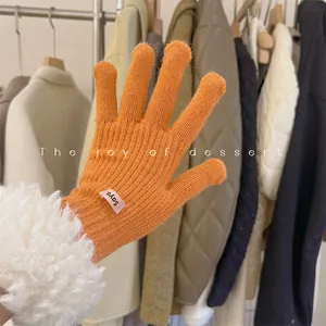 Close-up of bright orange knitted glove featuring soft white faux fur trim detail