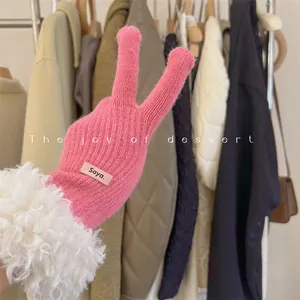 Detailed close-up of a pink knit winter glove featuring a plush white faux fur cuff and label.