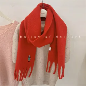 Close-up of cute girl embroidery on a thick red wool blend scarf with fringe details