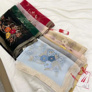 Close-up detail of various silk blend scarves with elegant begonia flower embroidery.