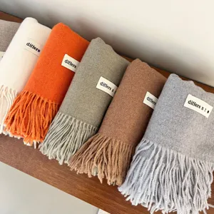 Row of colorful thick cashmere-like pashmina scarves with tassels and brand labels