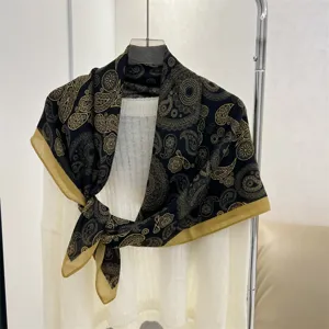 Elegant black and gold paisley 90cm square scarf styled on a white knit sweater.