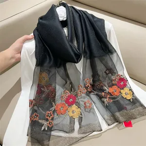 Close-up of elegant floral embroidery and metallic edges on a black silk-blend scarf