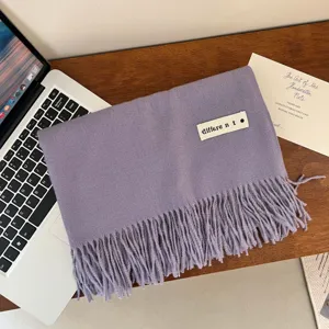 Detail view of a soft lavender purple imitation cashmere scarf with fringe and a brand patch