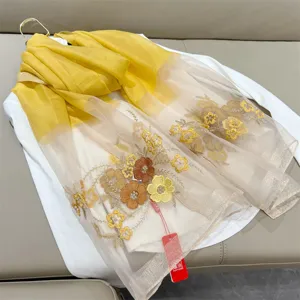 Detail of elegant begonia flower embroidery on a yellow silk blend scarf for women