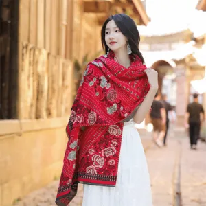 Detail view of an ethnic style red floral shawl on a model in a travel setting