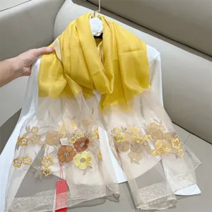 Close-up detail of yellow silk blend scarf featuring elegant begonia floral embroidery