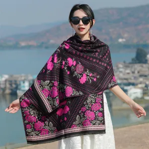 Detail view of an ethnic floral shawl featuring vibrant pink roses on black fabric