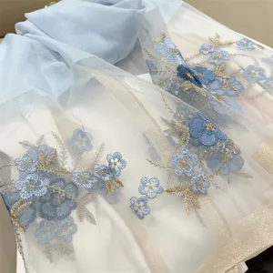 Close-up view of elegant blue begonia floral embroidery on a white silk blend scarf