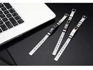 Close-up of three religious cross stainless steel mesh bracelets next to a laptop.