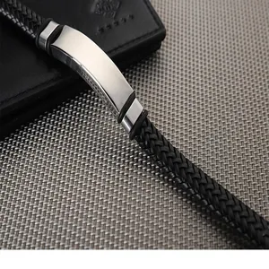 Close-up of a stylish black braided leather bracelet with a polished blank metal plate.