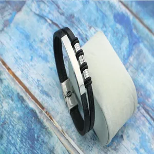 Detailed view of men's stainless steel woven leather bracelet on a display cushion