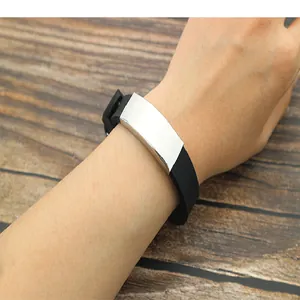 Closeup of minimalist black silicone wristband with blank metal ID plate on wooden background.