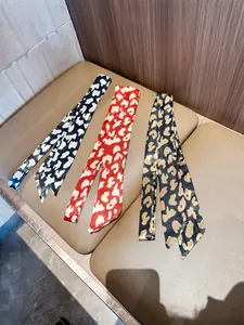 Elegante zijden sjaals met luipaardprint in drie kleuren plat op een beige kussen