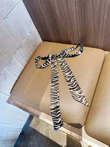 Detail van een chique smalle sjaal met zebraprint geknoopt in een strik voor haar