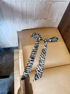 Gedetailleerd overzicht van een zijden lint met zebraprint in een strik op een lederen stoel