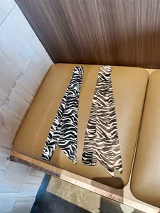 Gedetailleerd overzicht van twee elegante smalle zijden sjaals met zebra- en tijgerprints