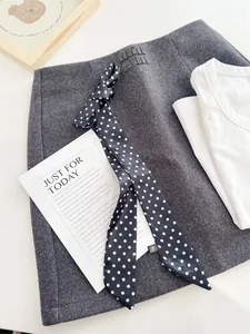 Detailopname van een elegante zwart-witte zijden sjaal met stippen als stijlvol haarlint.