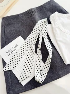 Detailweergave van een witte smalle sjaal met een klassiek zwart polkadots patroon