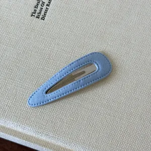 Primo piano di un fermaglio per capelli in tessuto azzurro con cuciture a vista fini