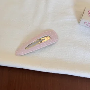 Détail d'une pince à cheveux rose à pois en tissu sur fond de tissu blanc