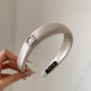 Detailansicht von cremefarbenem Satin-Haarreif mit schimmernder quadratischer Kristallschnalle