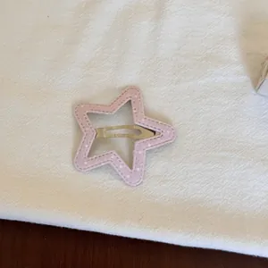 Vue détaillée d'une pince à cheveux en tissu rose en forme d'étoile à pois blancs