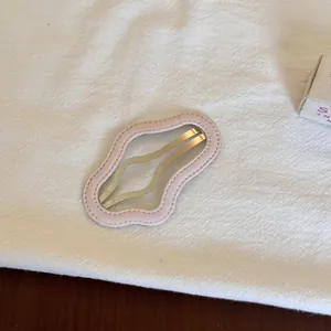 Détail d'une pince à cheveux rose ondulée sur un fond de tissu texturé blanc très doux