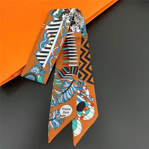 Close-up of a vibrant patterned twilly scarf draped elegantly over an orange gift bag