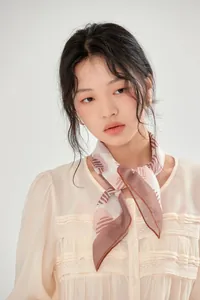 Close-up of a model wearing a French vintage printed cotton square scarf in beige and brown.