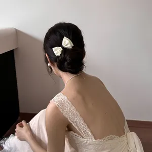 Detail view of an elegant cream polka dot bow hair comb styled in a French bun.